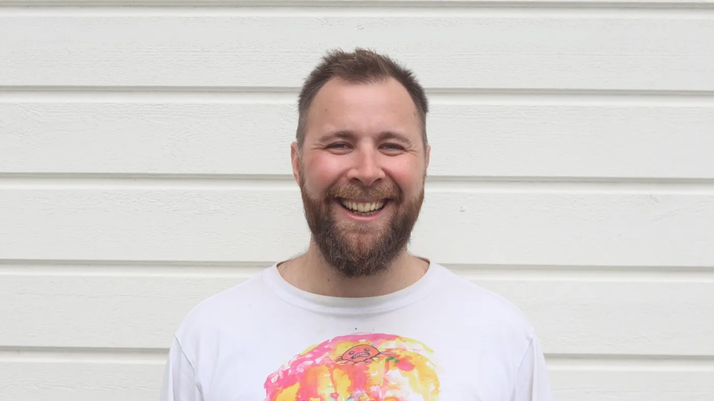 Marcus Tigerdraake skrattar framför en vit panelvägg